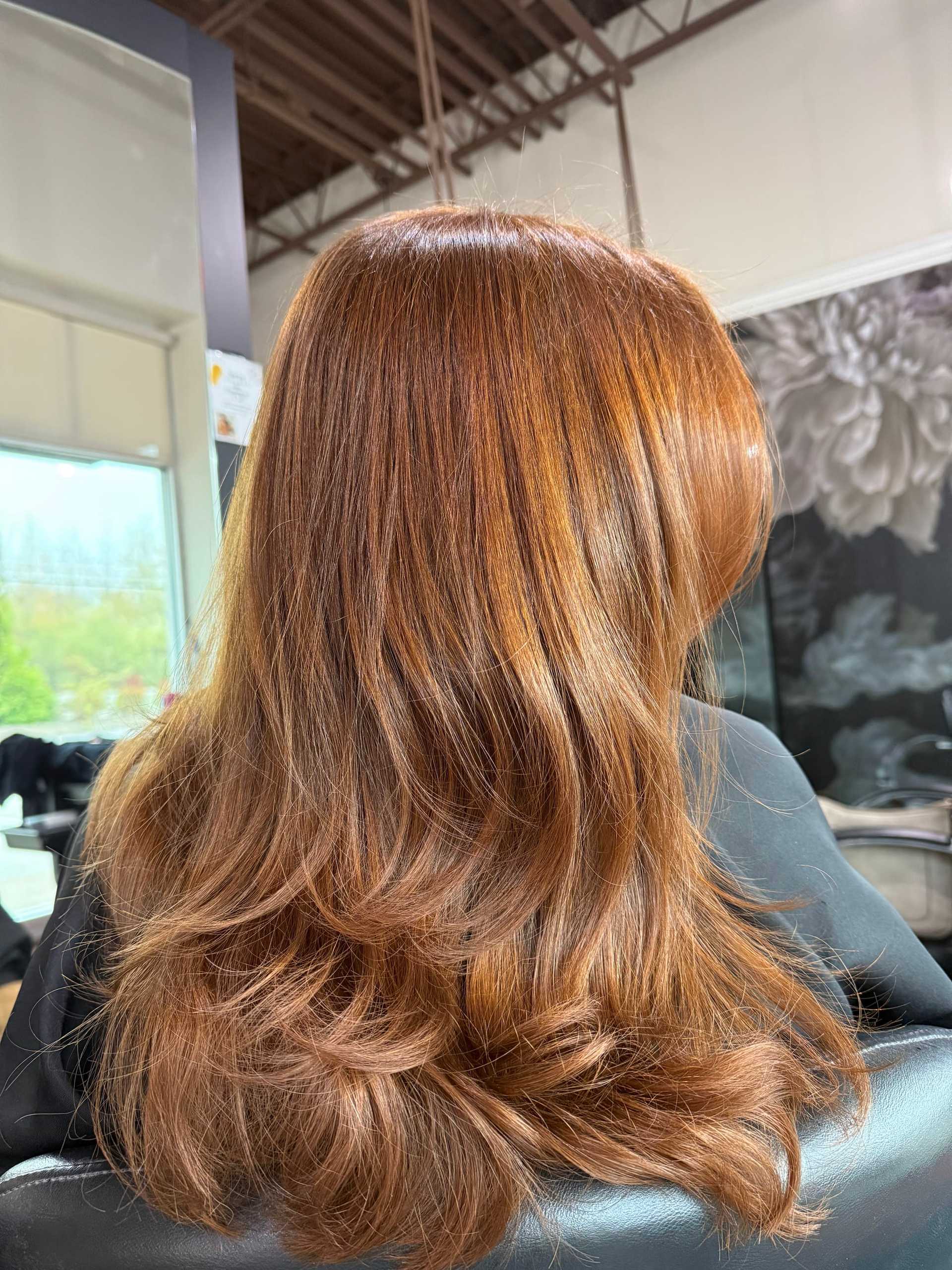 Red-brown hair with soft waves in a salon setting.